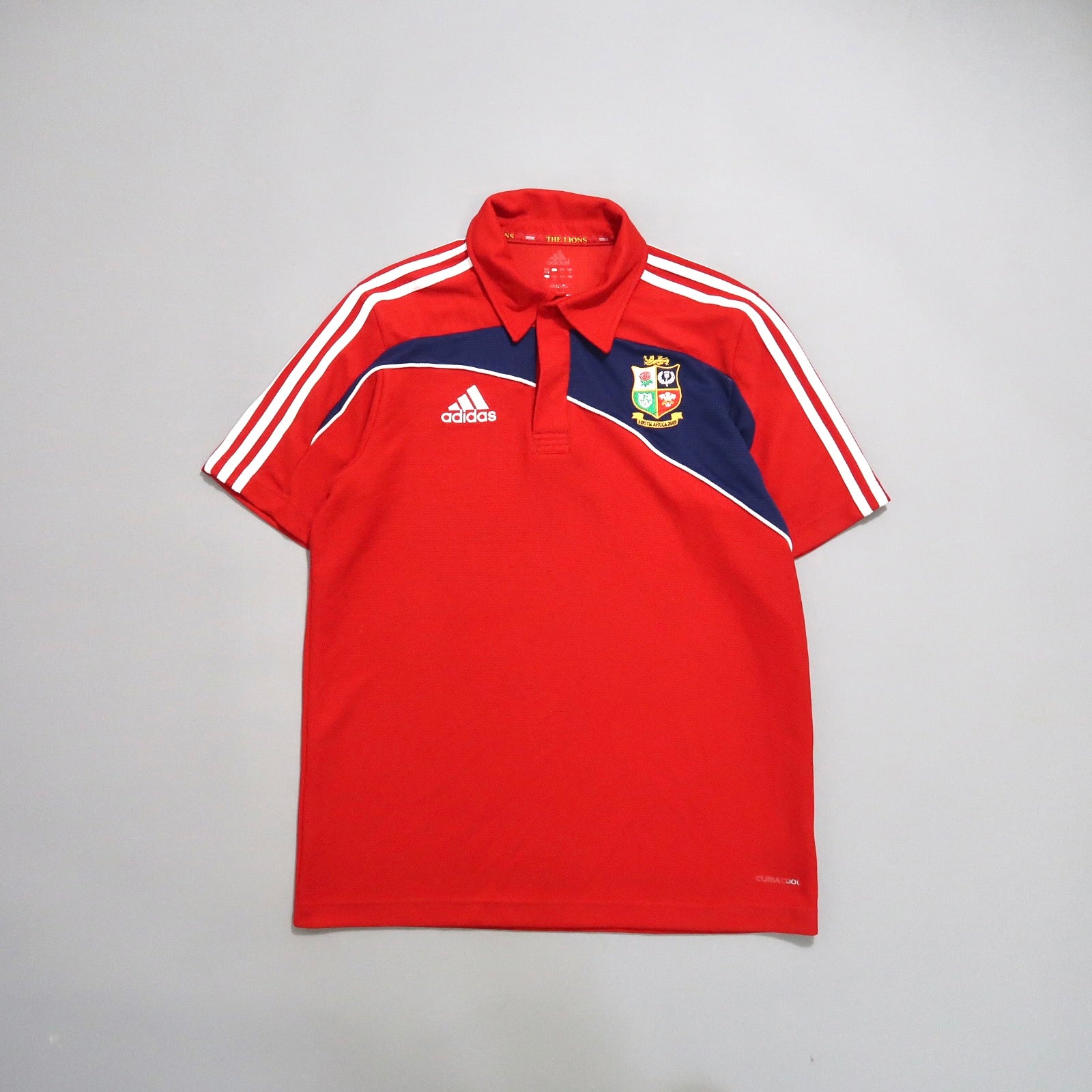 Red Adidas polo with stripes and a sports team crest.
