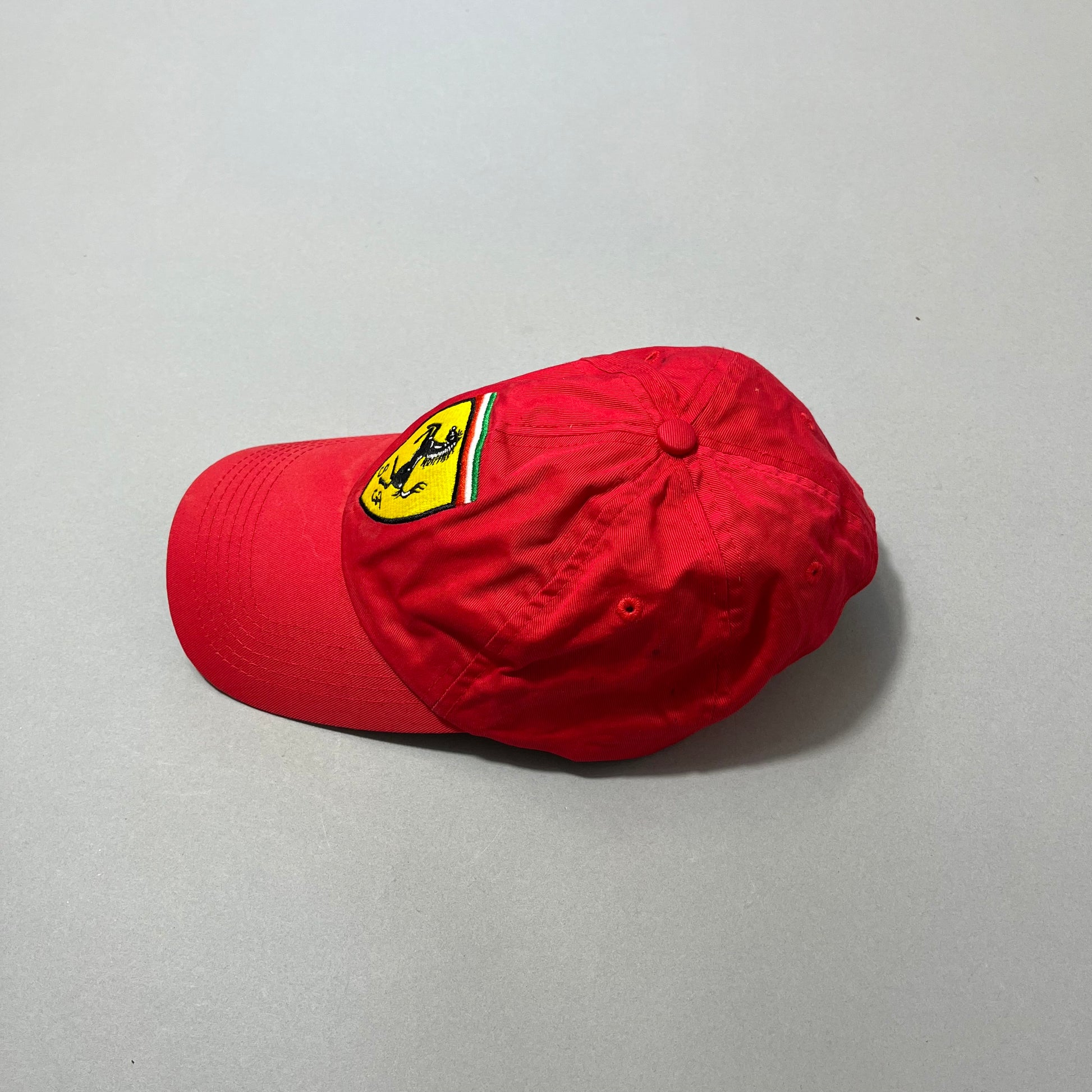 Red cap with yellow logo on a gray background.
