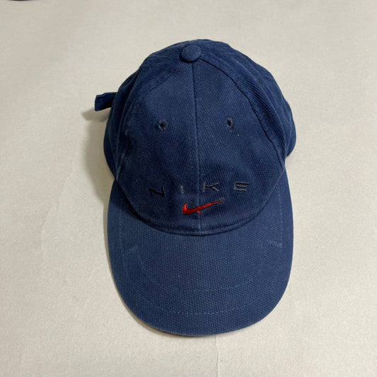 Blue Nike cap with a red logo on a neutral background.