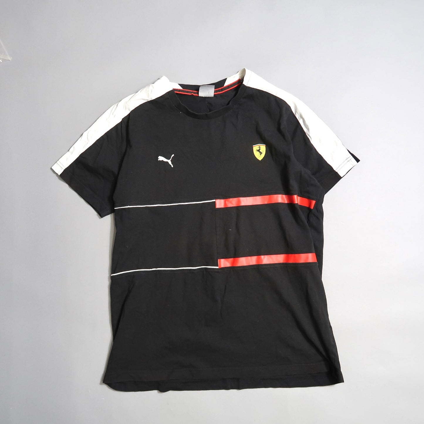 Black T-shirt with red stripes, Puma logo, and yellow shield emblem.