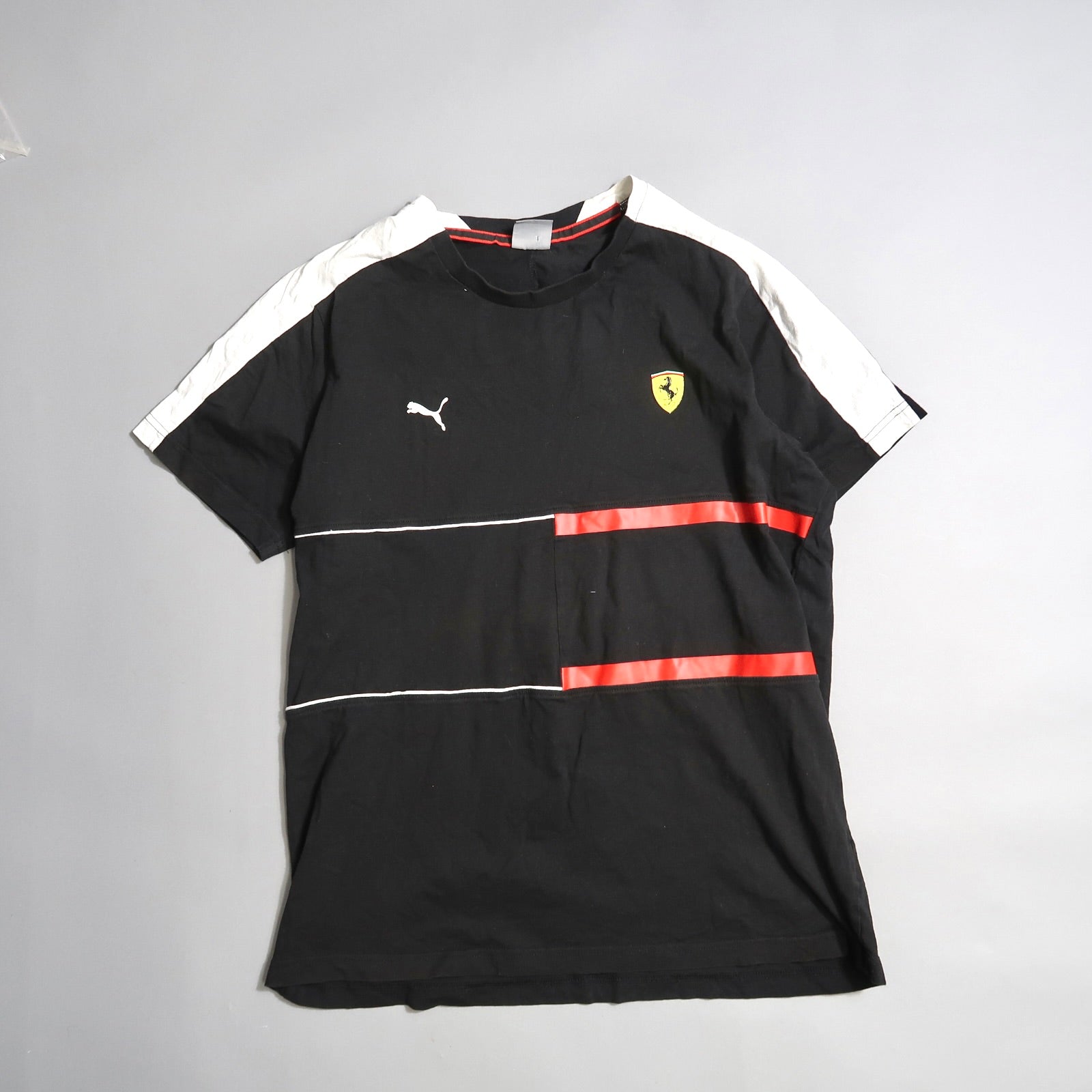 Black T-shirt with red stripes, Puma logo, and yellow shield emblem.