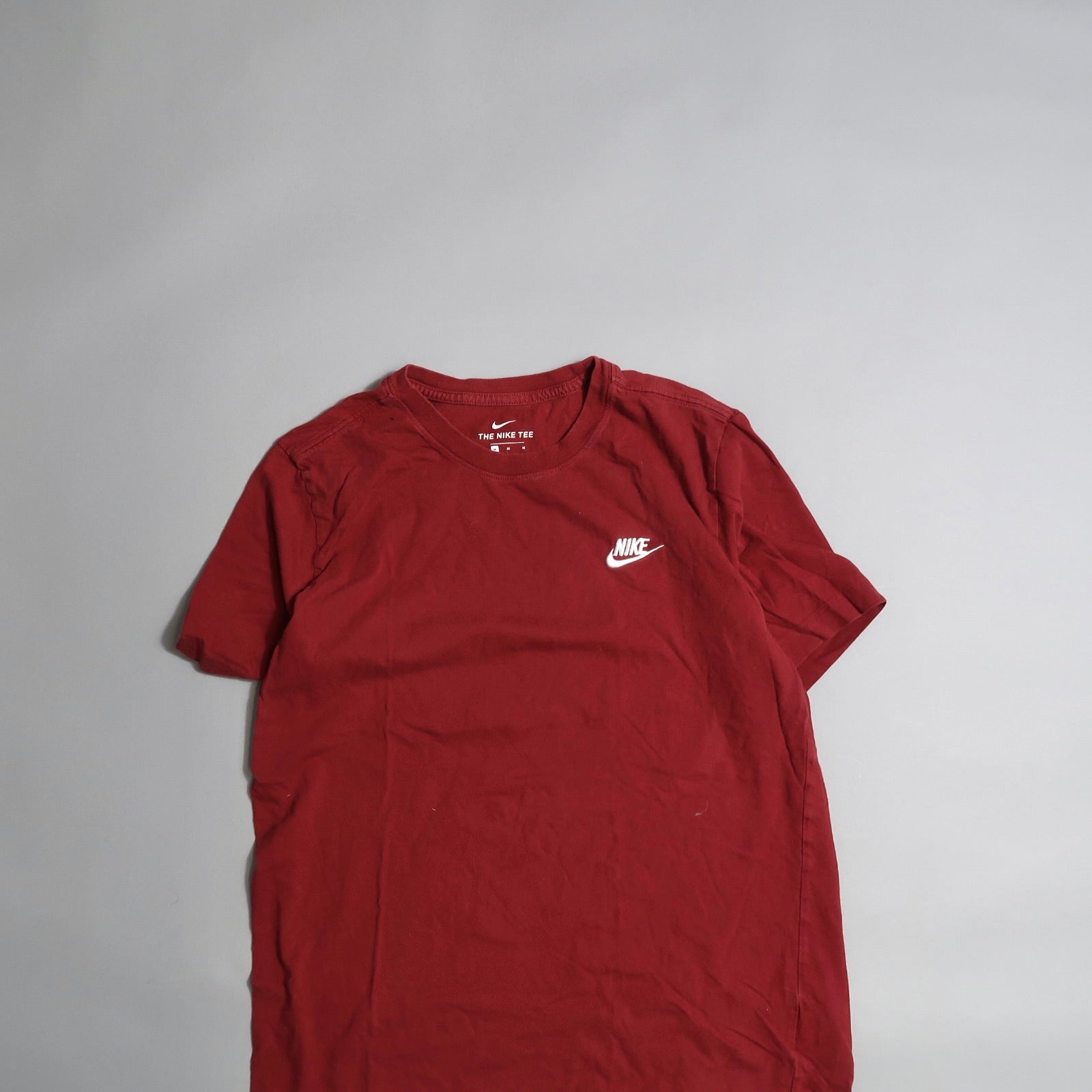Red Nike T-shirt with logo displayed on a neutral background.