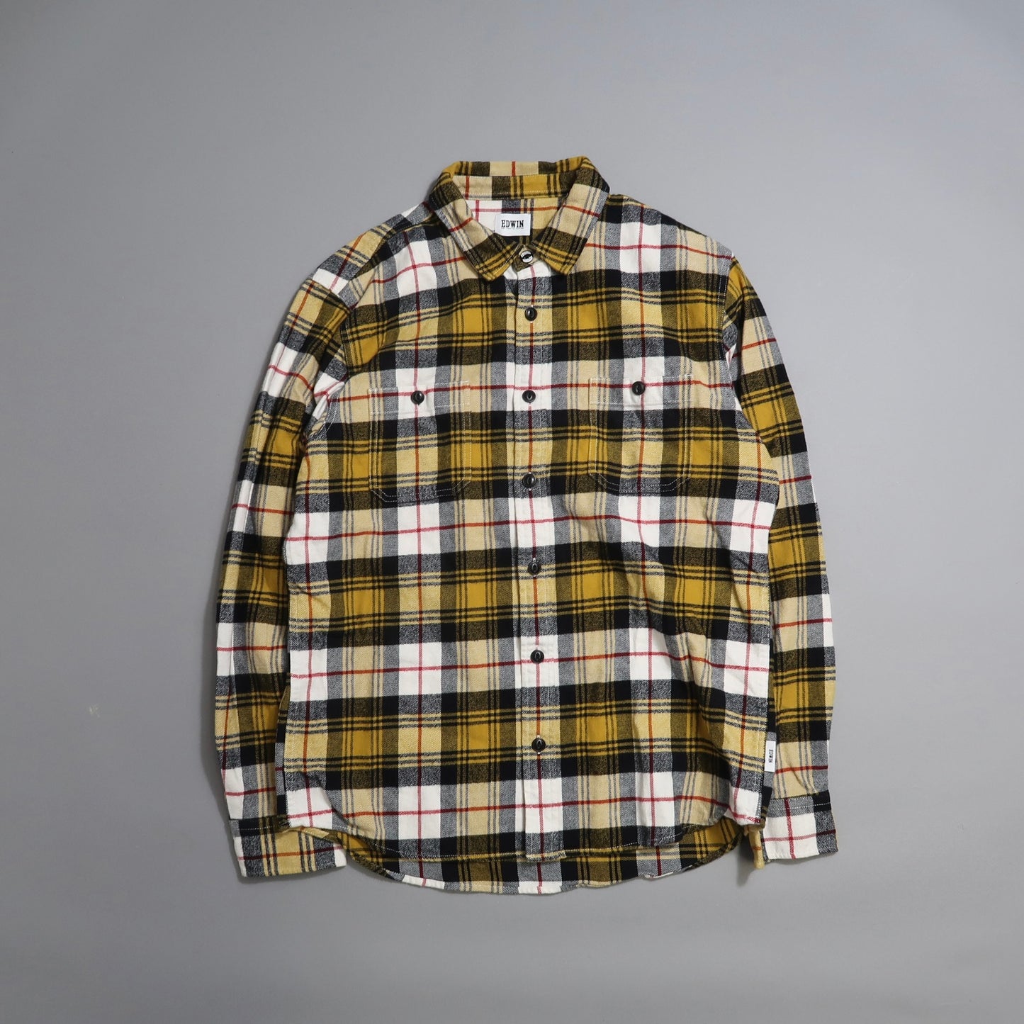 Yellow, black, and white plaid shirt on a gray background.