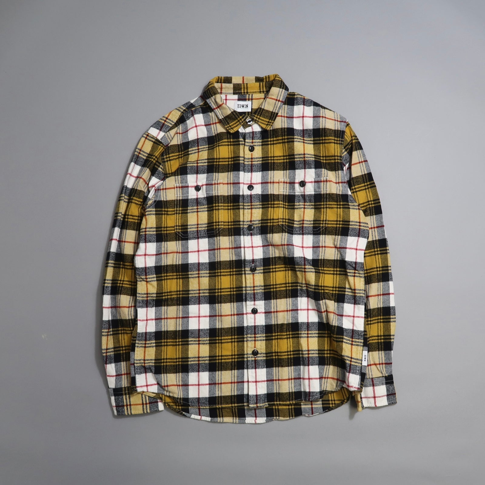 Yellow, black, and white plaid shirt on a gray background.