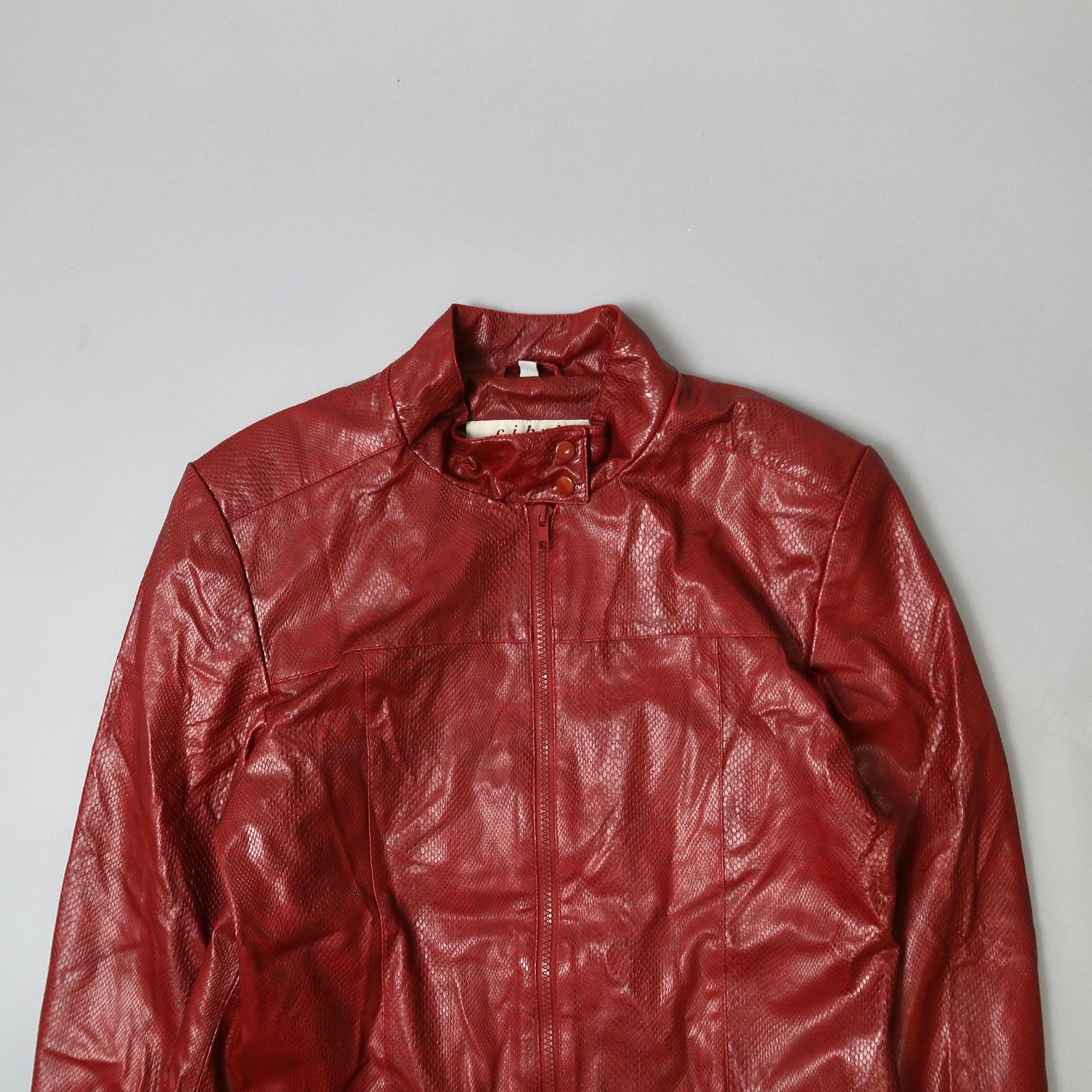 Red leather jacket with a textured finish on a plain background.