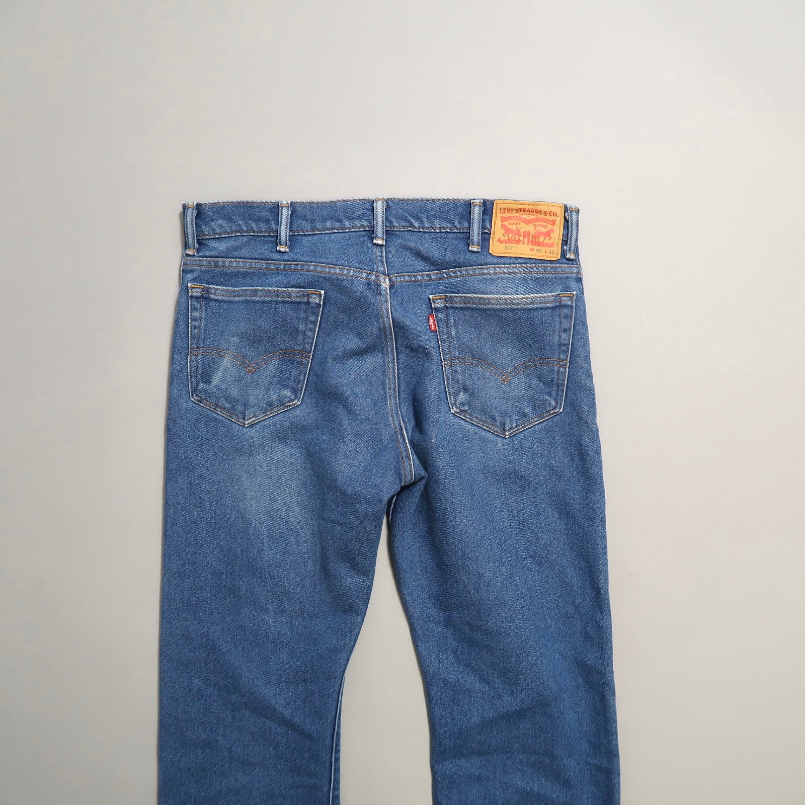 Back view of blue denim jeans with leather patch and pockets.