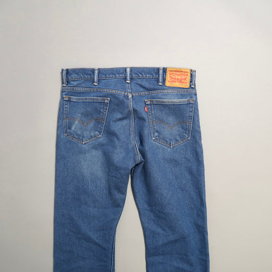 Back view of blue denim jeans with leather patch and pockets.