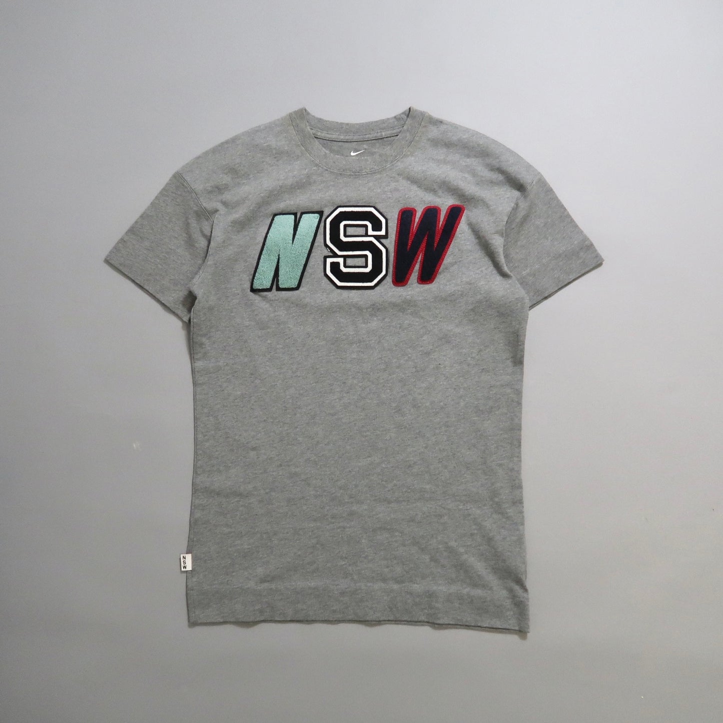 Gray T-shirt with large nullNSWnull letters on the front.