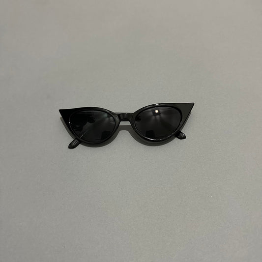Black cat-eye sunglasses on a plain gray background.