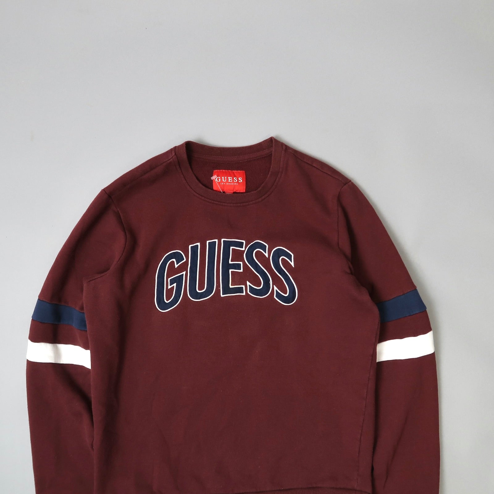 Burgundy Guess sweatshirt with navy and white sleeve stripes.