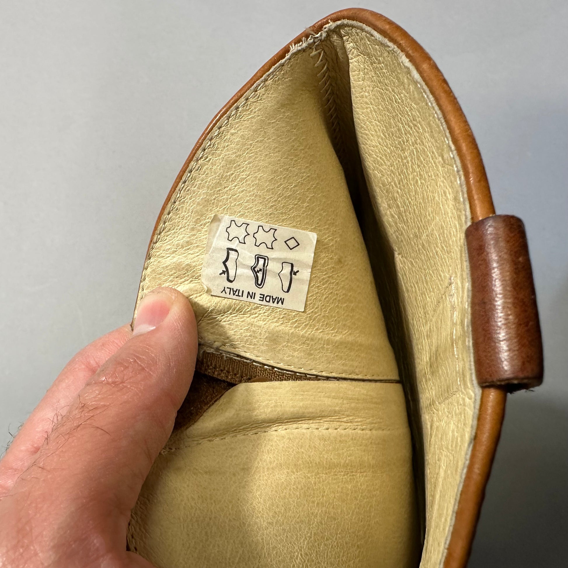 Hand holding a leather item labeled nullMade in Italynull.