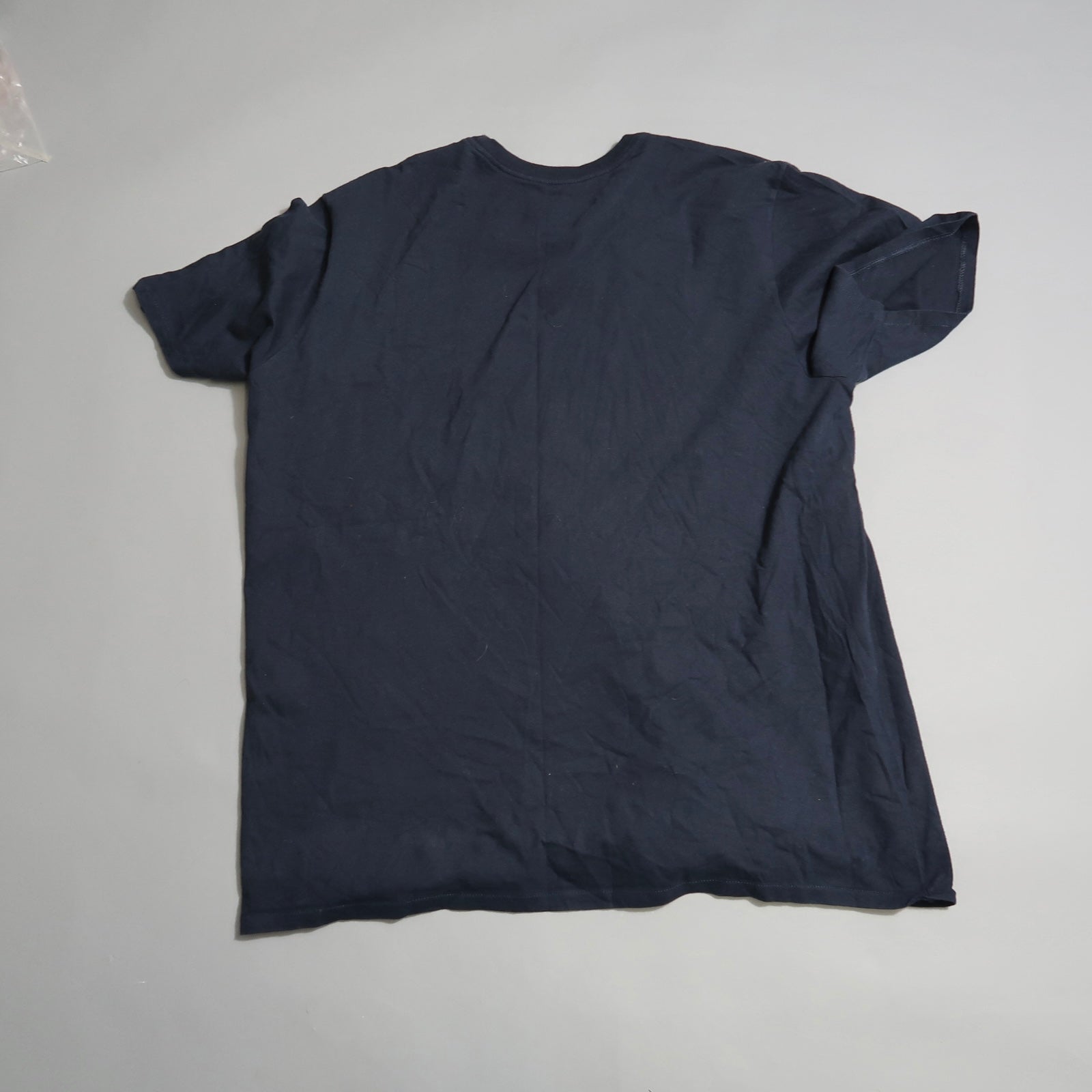 Dark blue T-shirt lying flat on a gray surface.