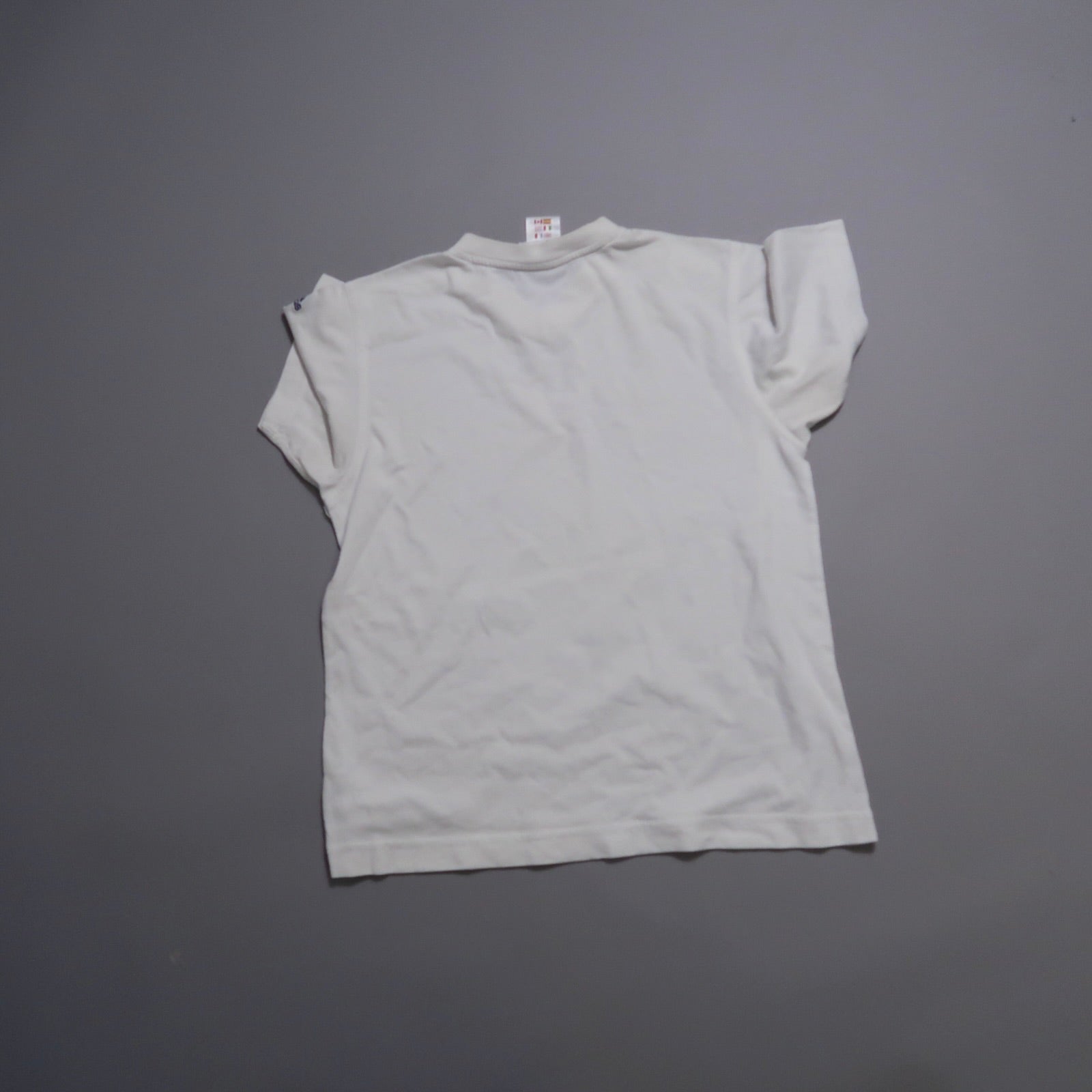 White T-shirt laid flat on a gray surface, viewed from the back.