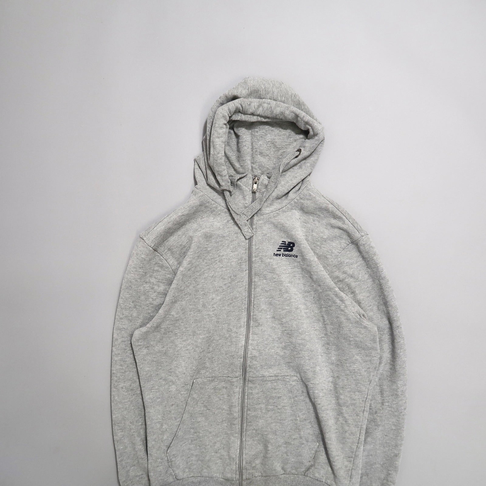 Gray New Balance hoodie with a zipper, laid flat on a white background.