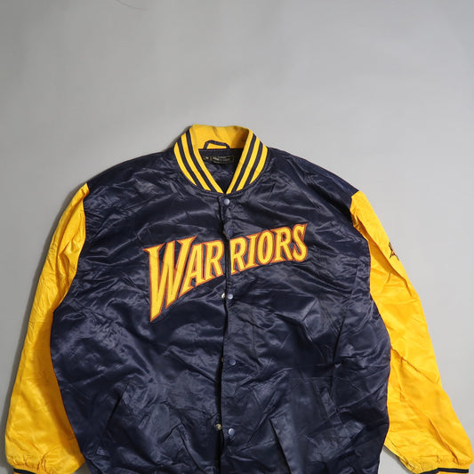 Blue and yellow Warriors jacket with striped collar on a gray background.