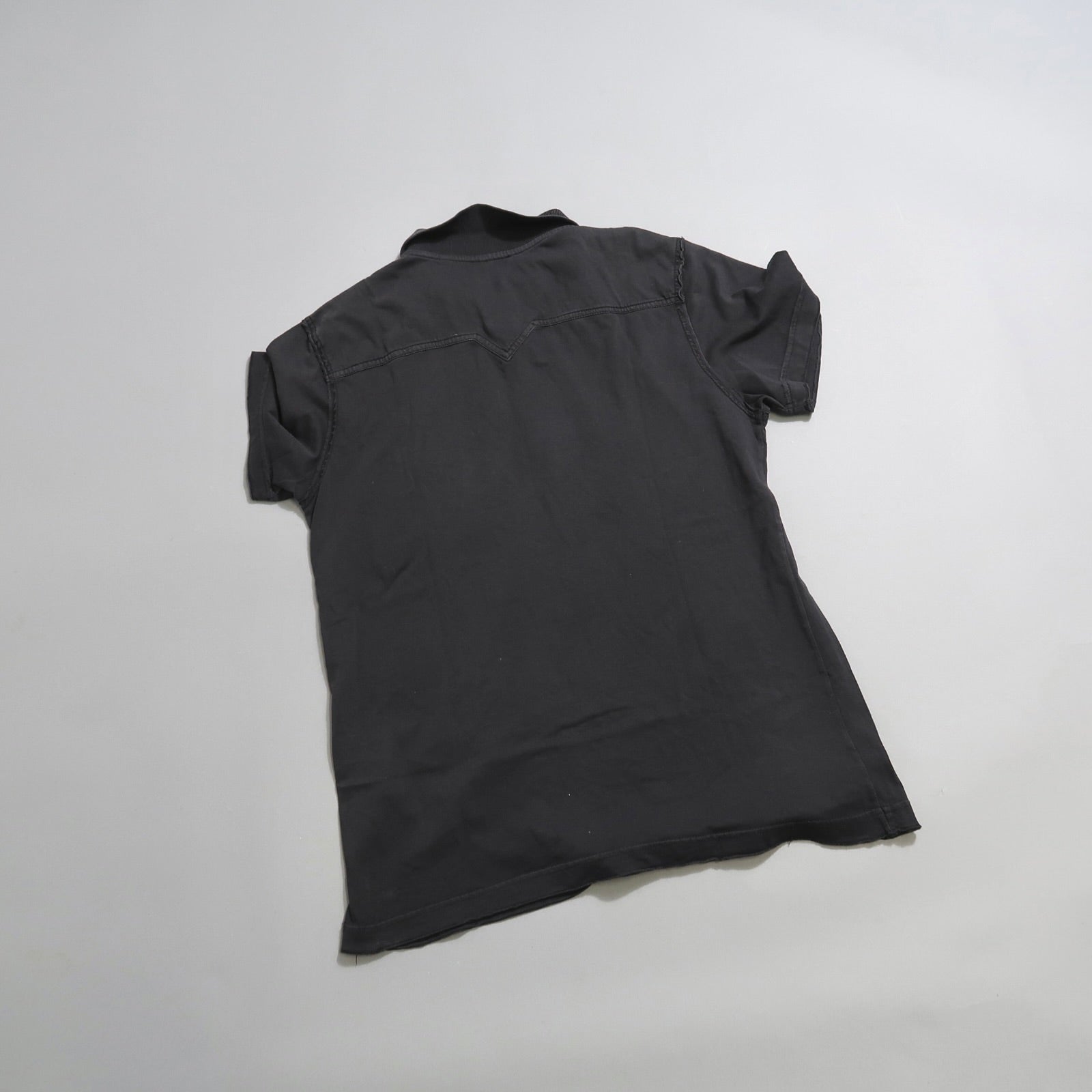 Back view of a short-sleeved dark shirt on a light background.