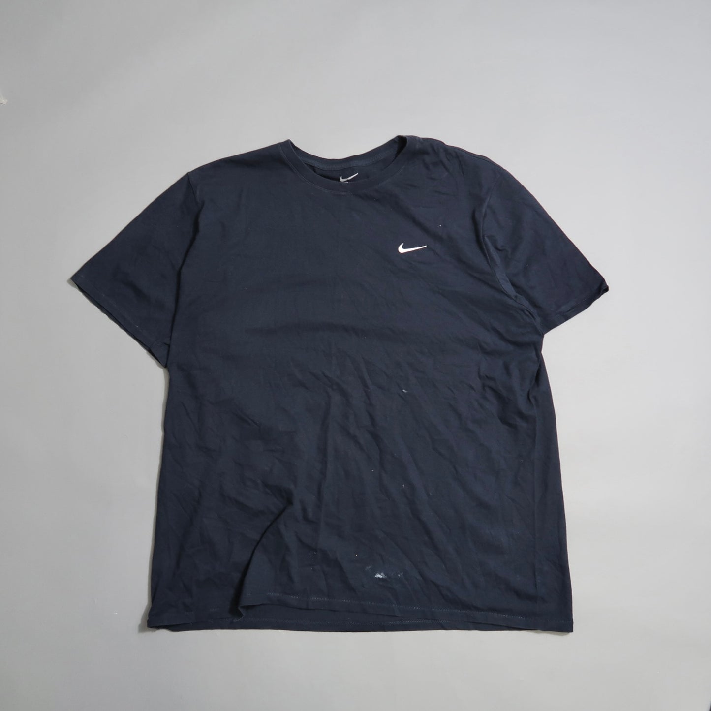 Black T-shirt with a small white swoosh logo on the left chest.