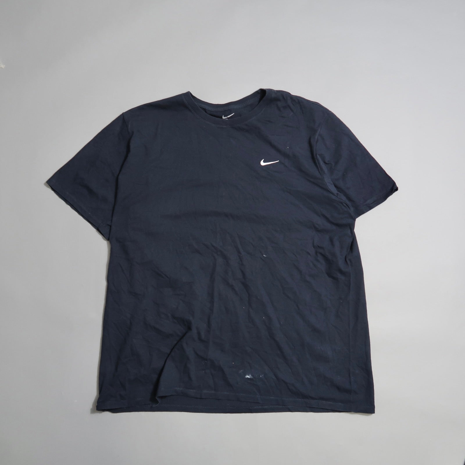Black T-shirt with a small white swoosh logo on the left chest.