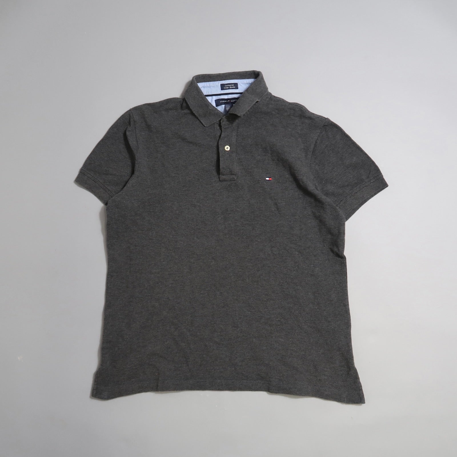 Dark gray polo shirt with a small logo on a plain background.