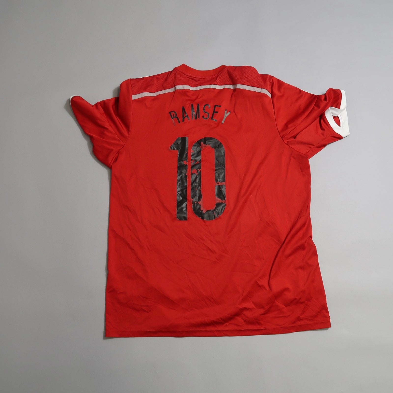 Red sports jersey with nullRamsey 10null on the back, lying flat.