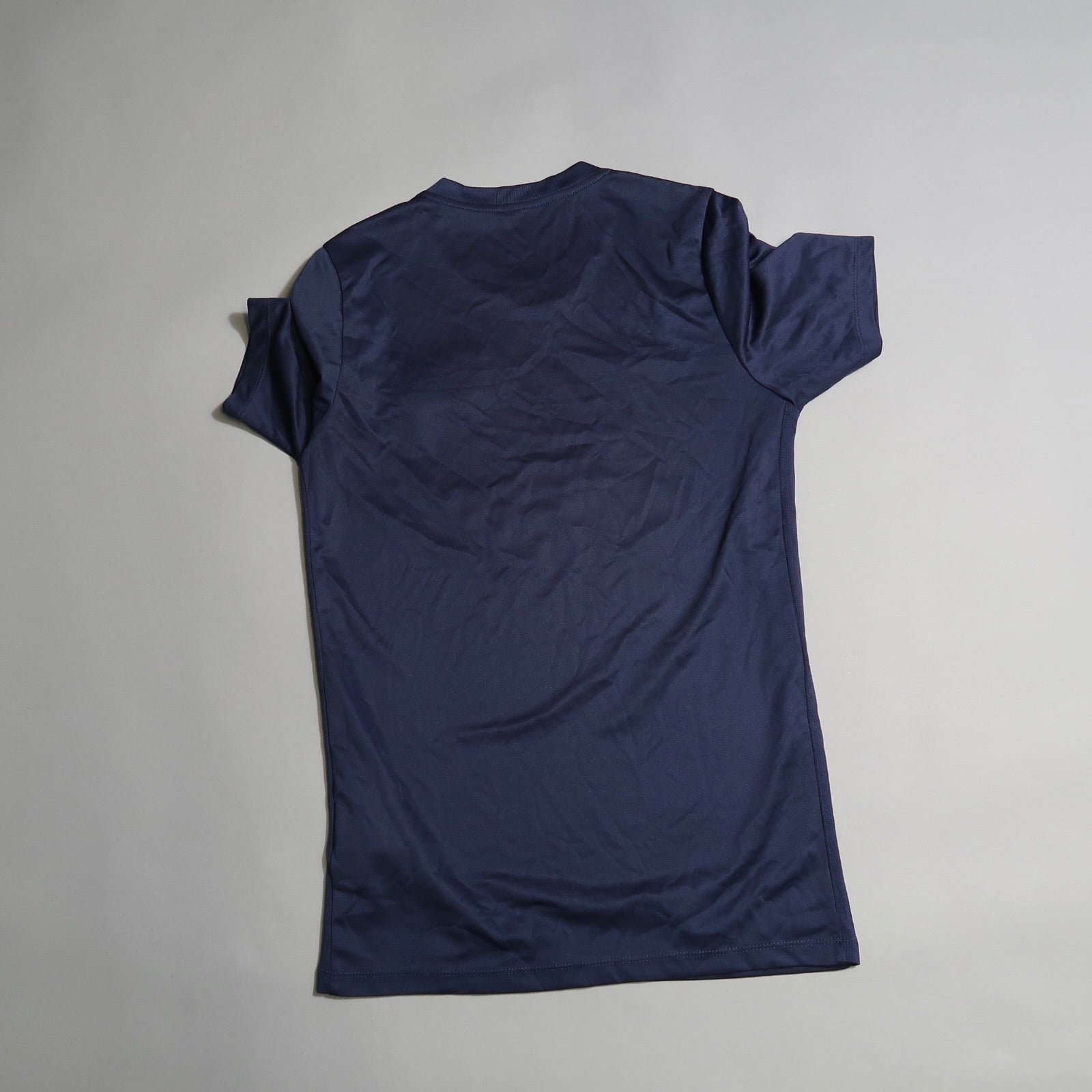 Back view of a plain navy blue t-shirt on a gray background.