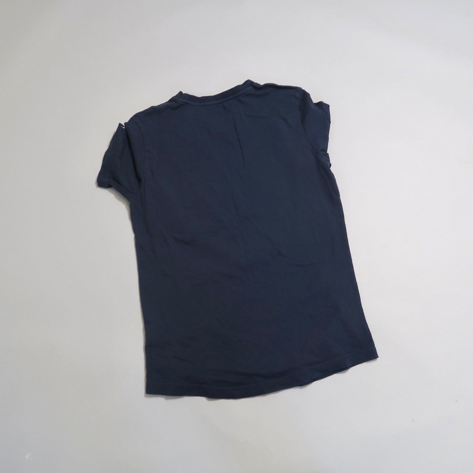 Navy blue T-shirt lying flat on a light surface.