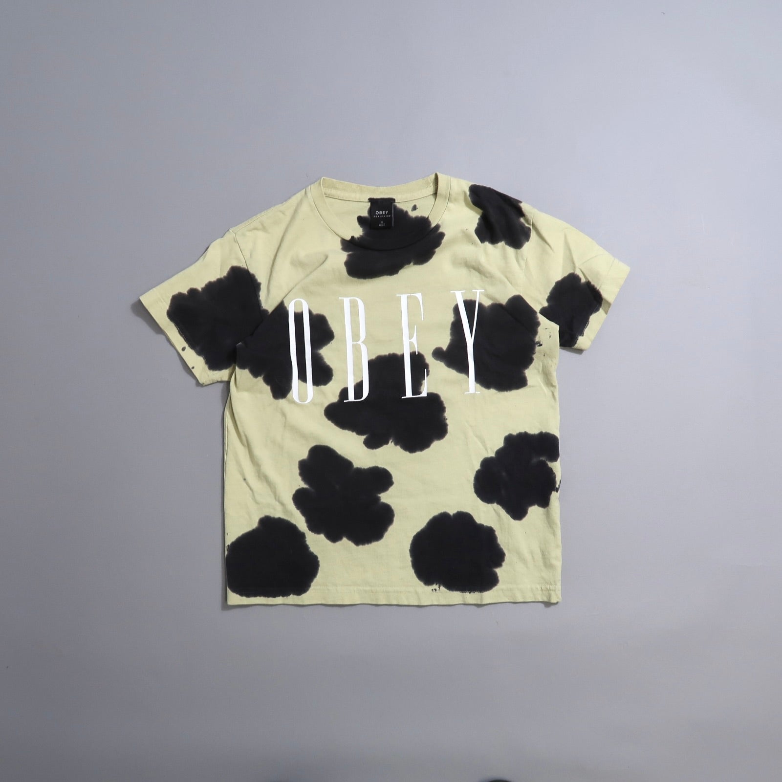 Beige t-shirt with black splotches and nullOBEYnull text.