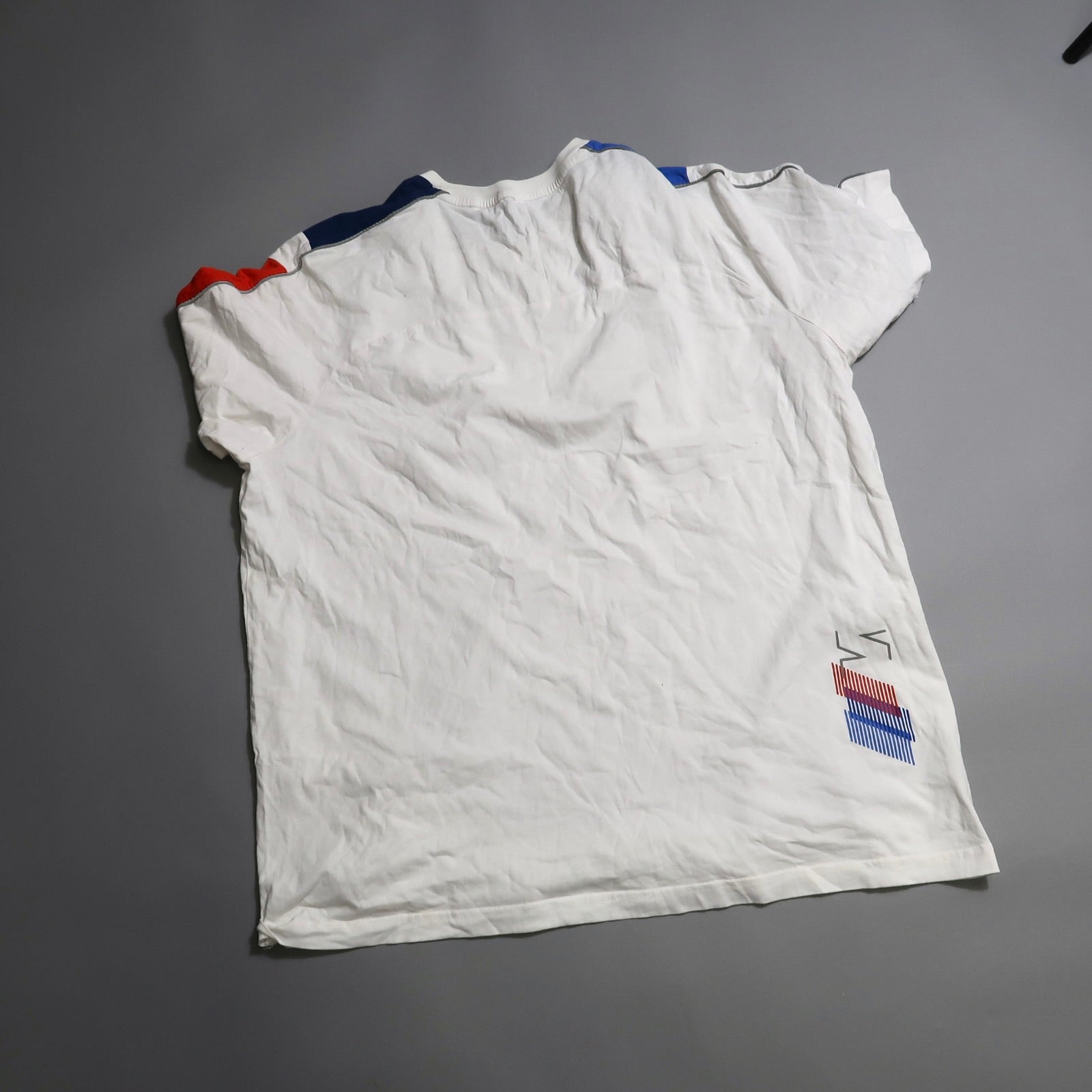 White t-shirt with colored shoulder stripes and graphic detail.