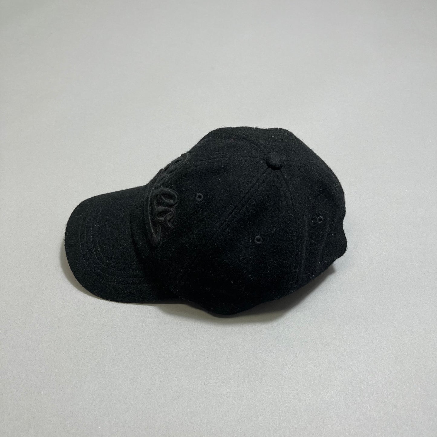 Black baseball cap with embroidered letters on a gray surface.