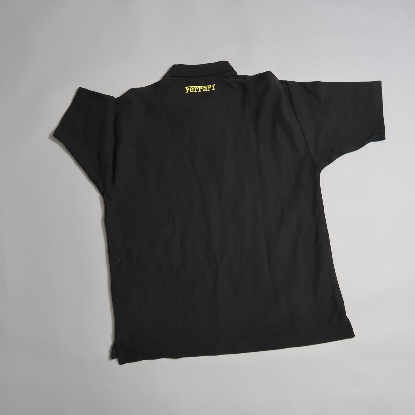Back view of a black T-shirt with yellow nullFerrarinull text near the collar.