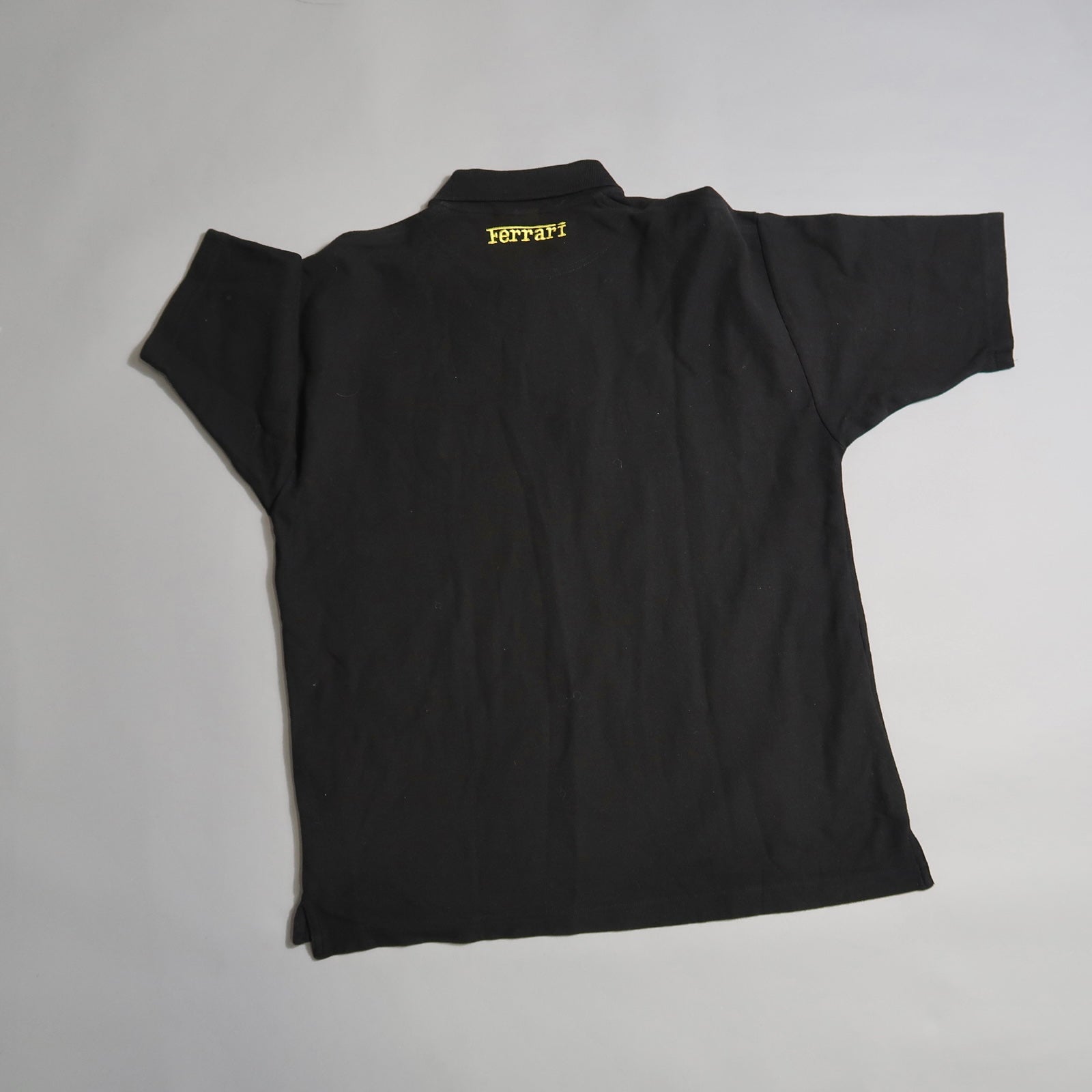 Back view of a black T-shirt with yellow nullFerrarinull text near the collar.