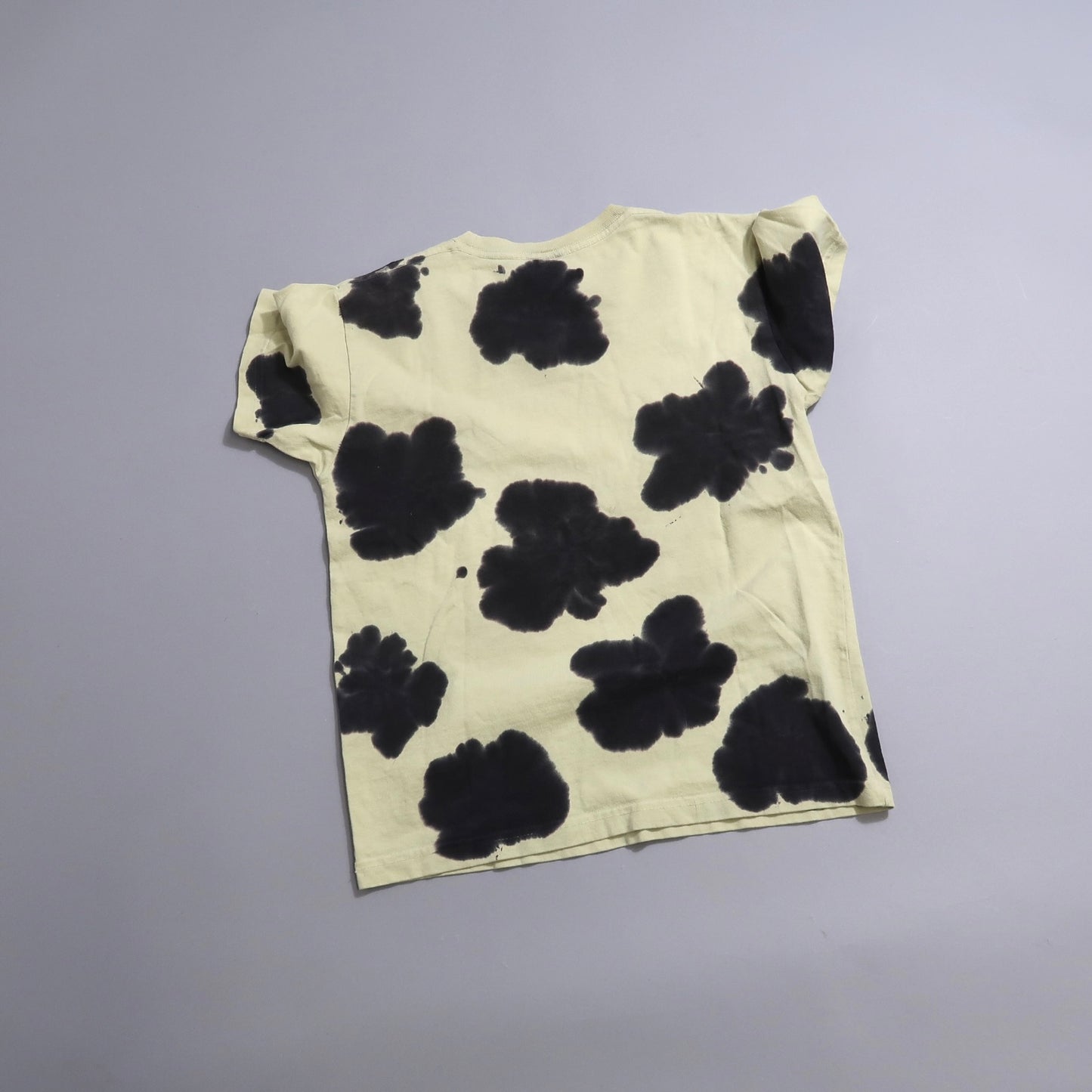 Tie-dye T-shirt with large black splotches on a light background.