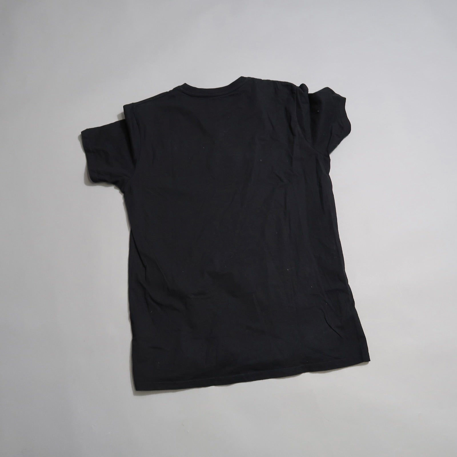 Black t-shirt laid flat on a light gray background.