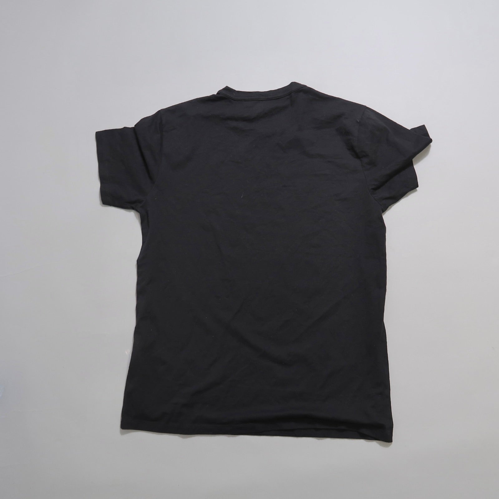 Back view of a plain black T-shirt on a neutral background.