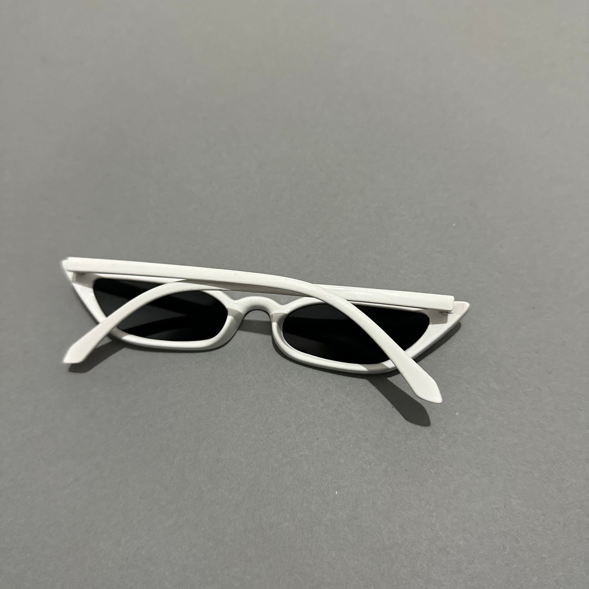White cat-eye sunglasses on a gray surface.