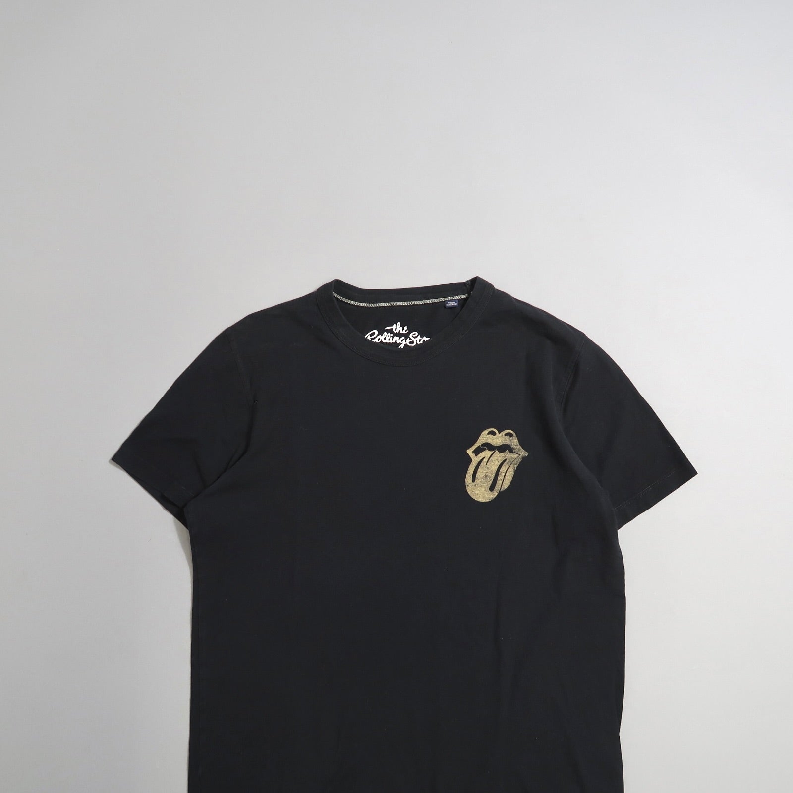 Black t-shirt with tongue and lips logo on the upper left.