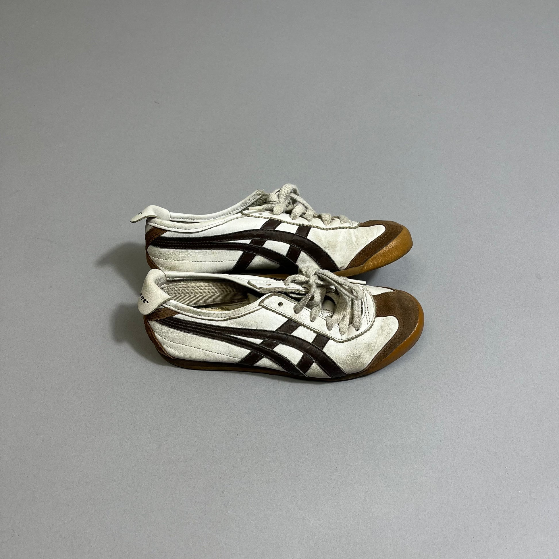 White and brown sneakers with black stripes on a gray background.