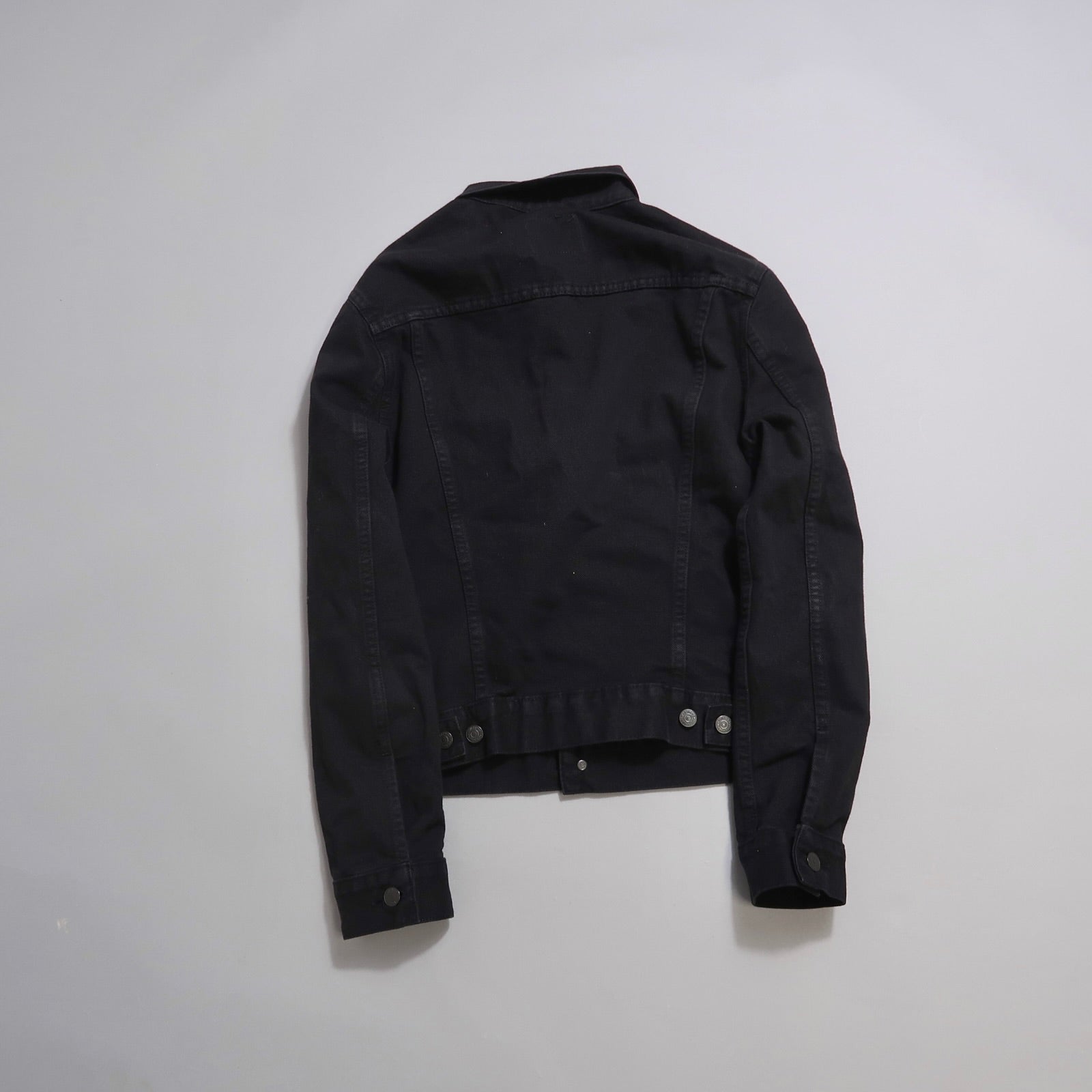 Black denim jacket displayed on a gray background.