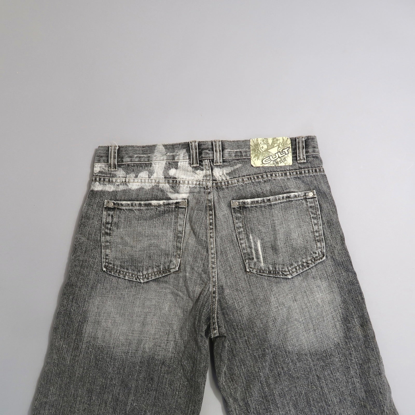 Back view of faded gray jeans with a nullCultnull label on the waistband.