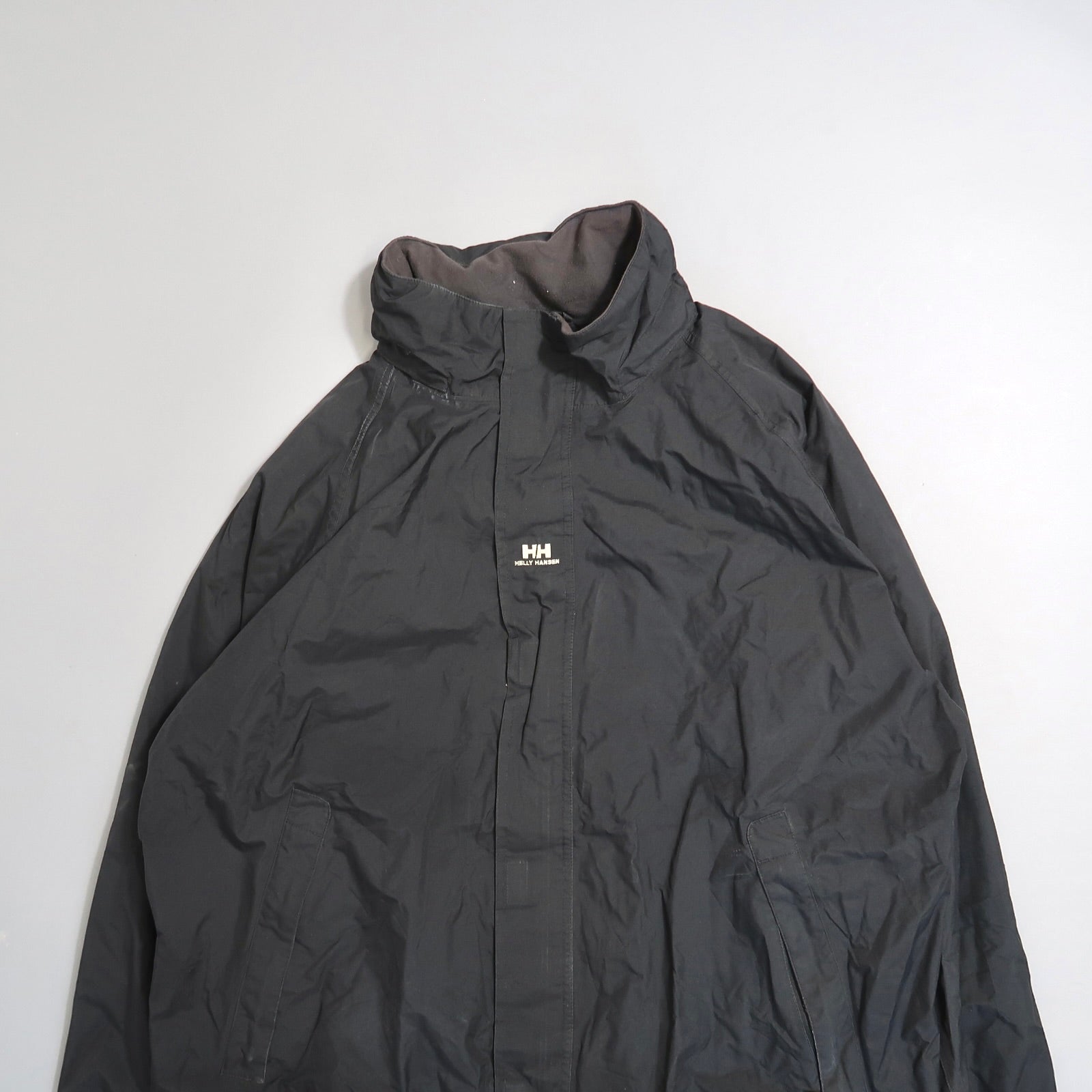 Black Helly Hansen jacket on a plain background.
