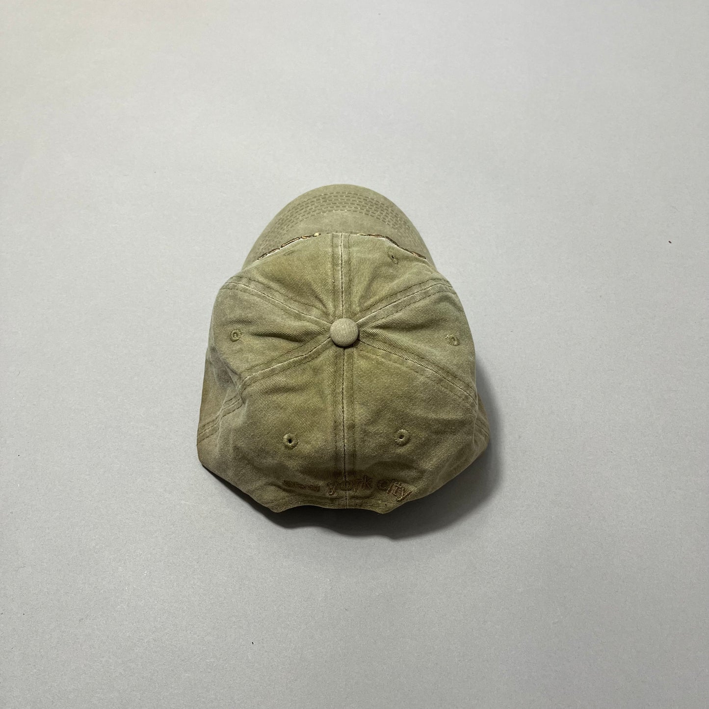 Worn tan baseball cap on a gray background.