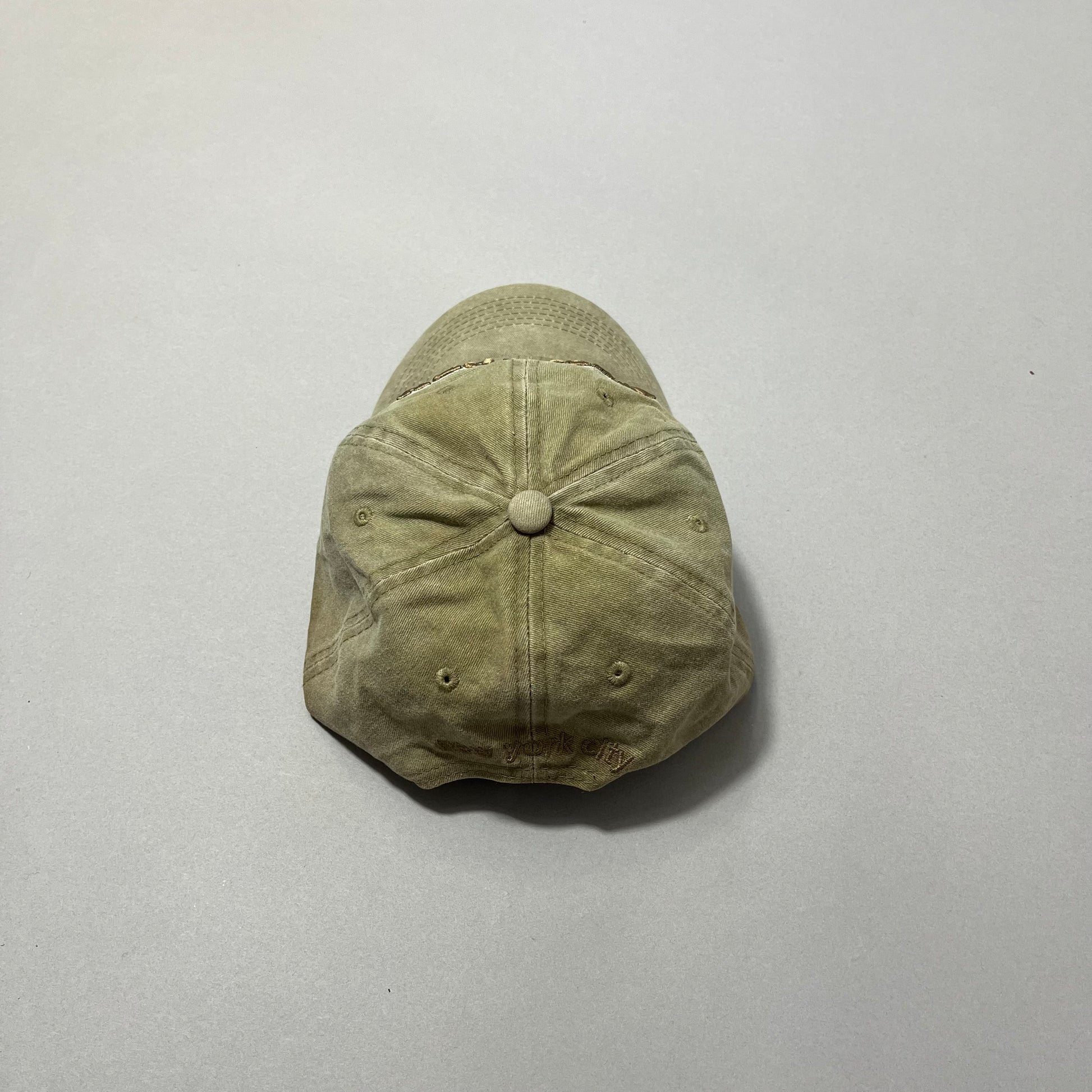 Worn tan baseball cap on a gray background.