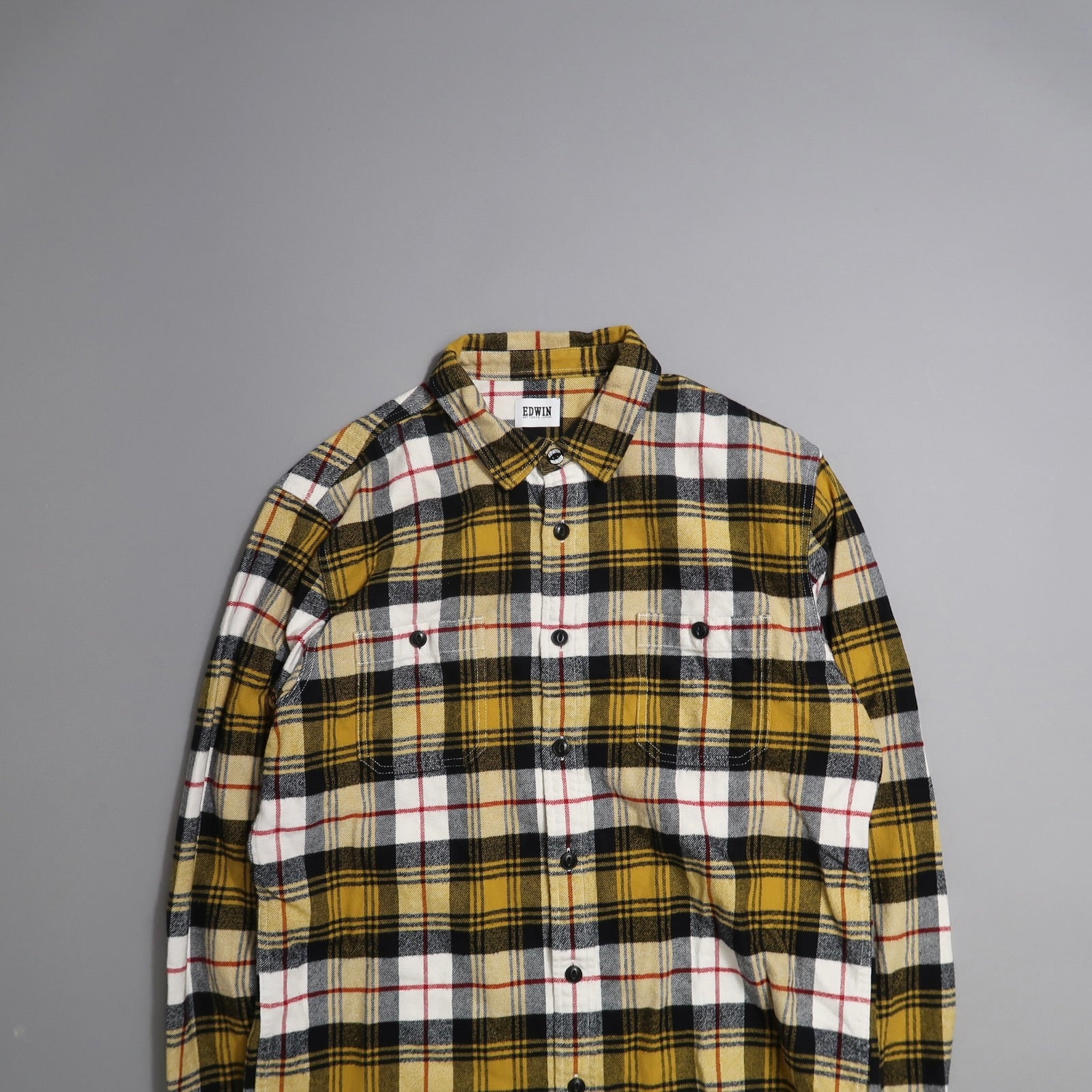 Yellow and black plaid flannel shirt on a gray background.