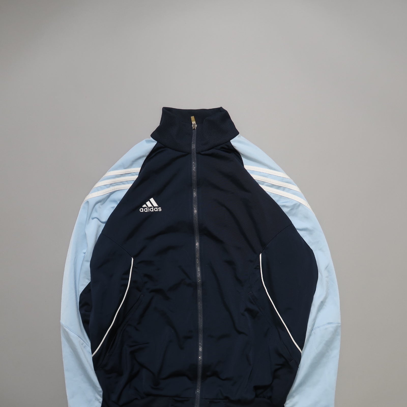 Navy and light blue Adidas track jacket with white stripes.