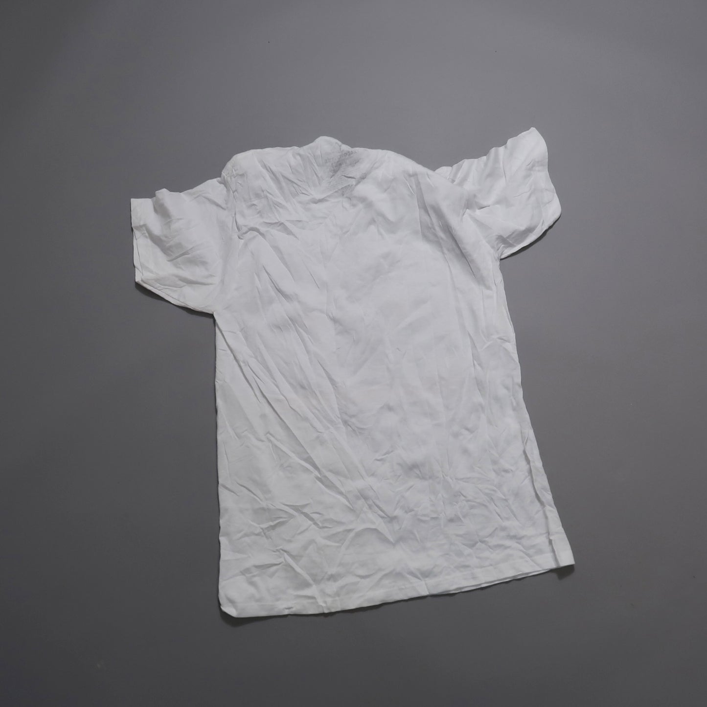White crumpled T-shirt on gray background.