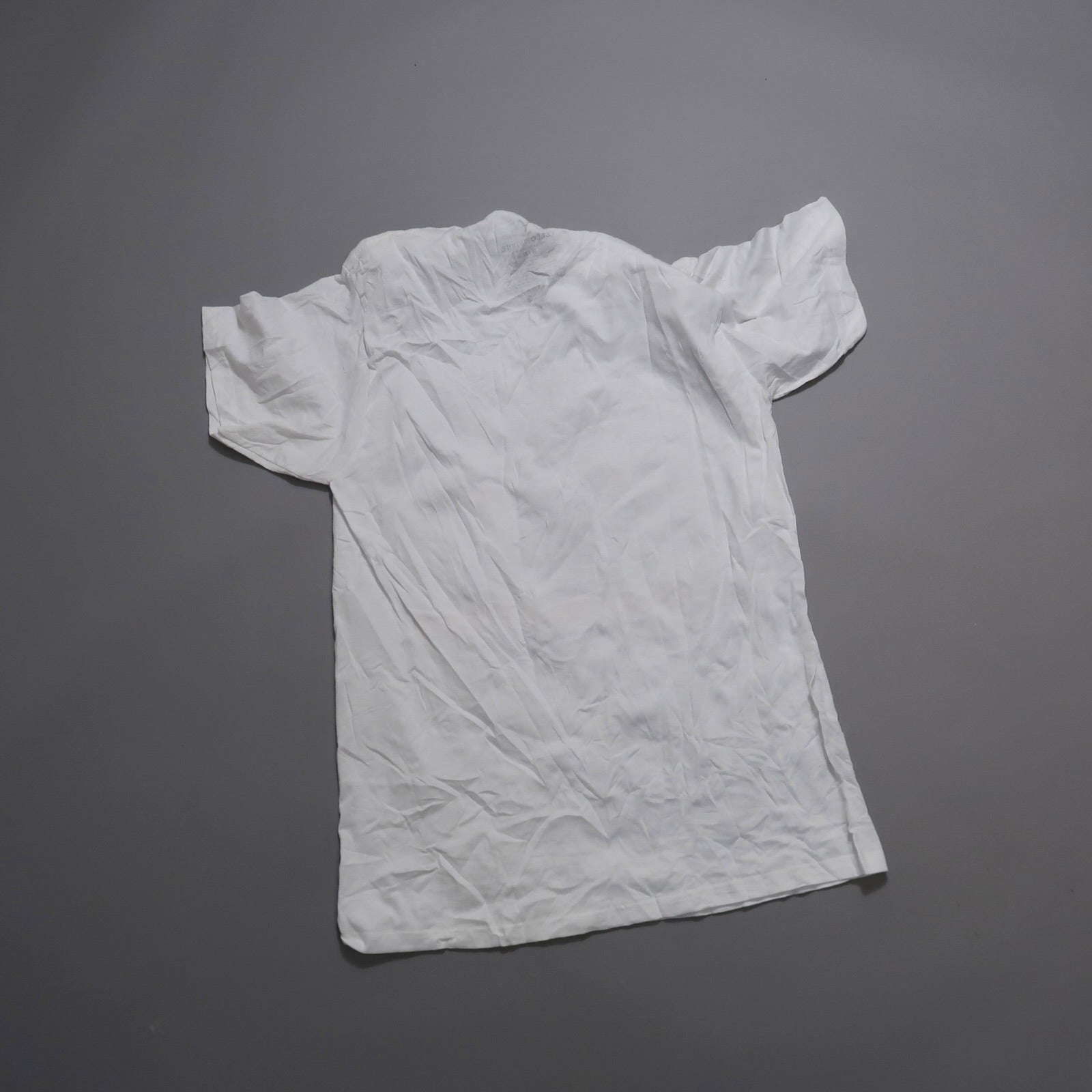 White crumpled T-shirt on gray background.