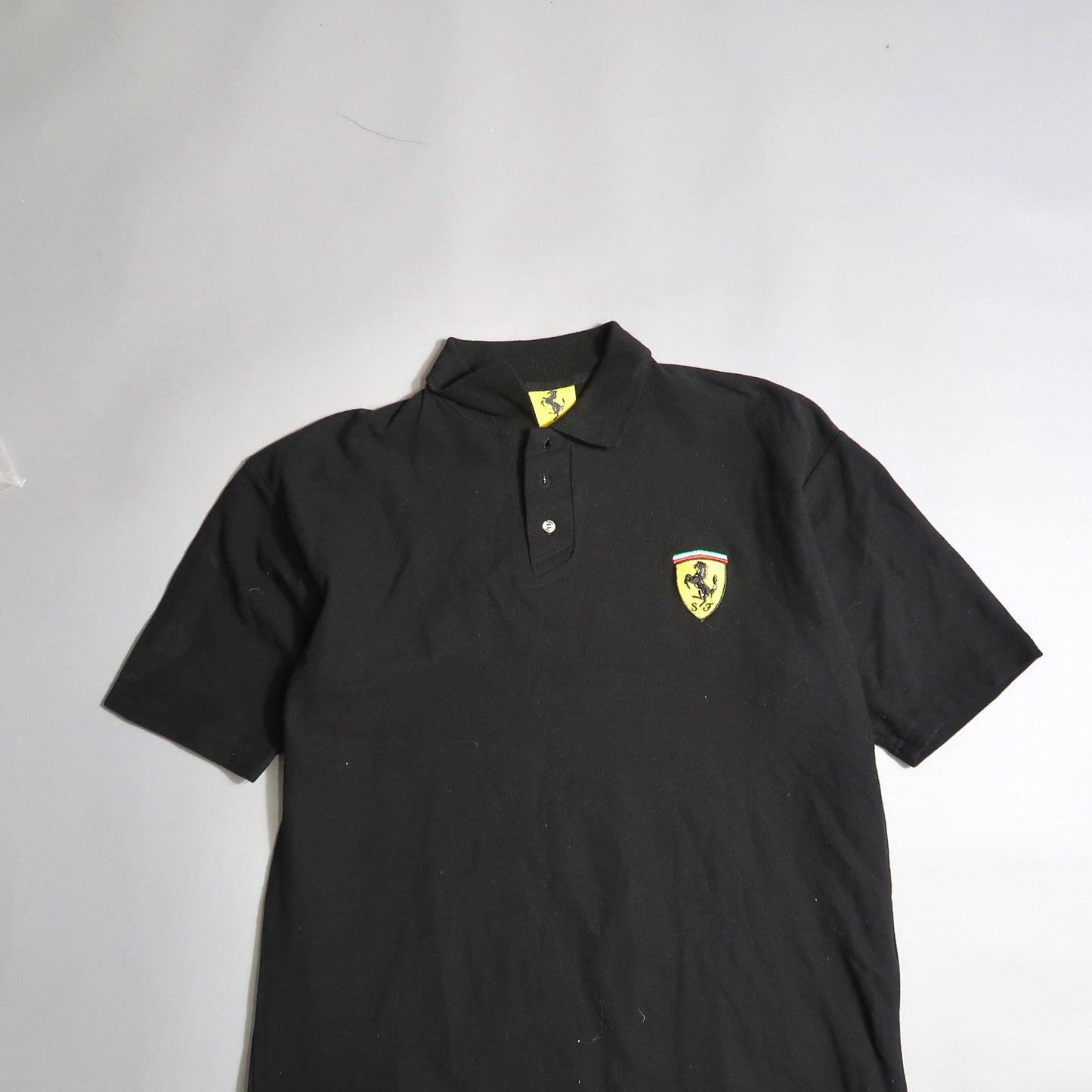 Black polo shirt with yellow logo on the chest.
