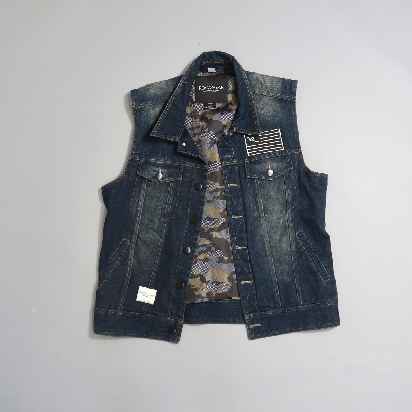 Denim vest with camouflage lining and logo patch on chest.