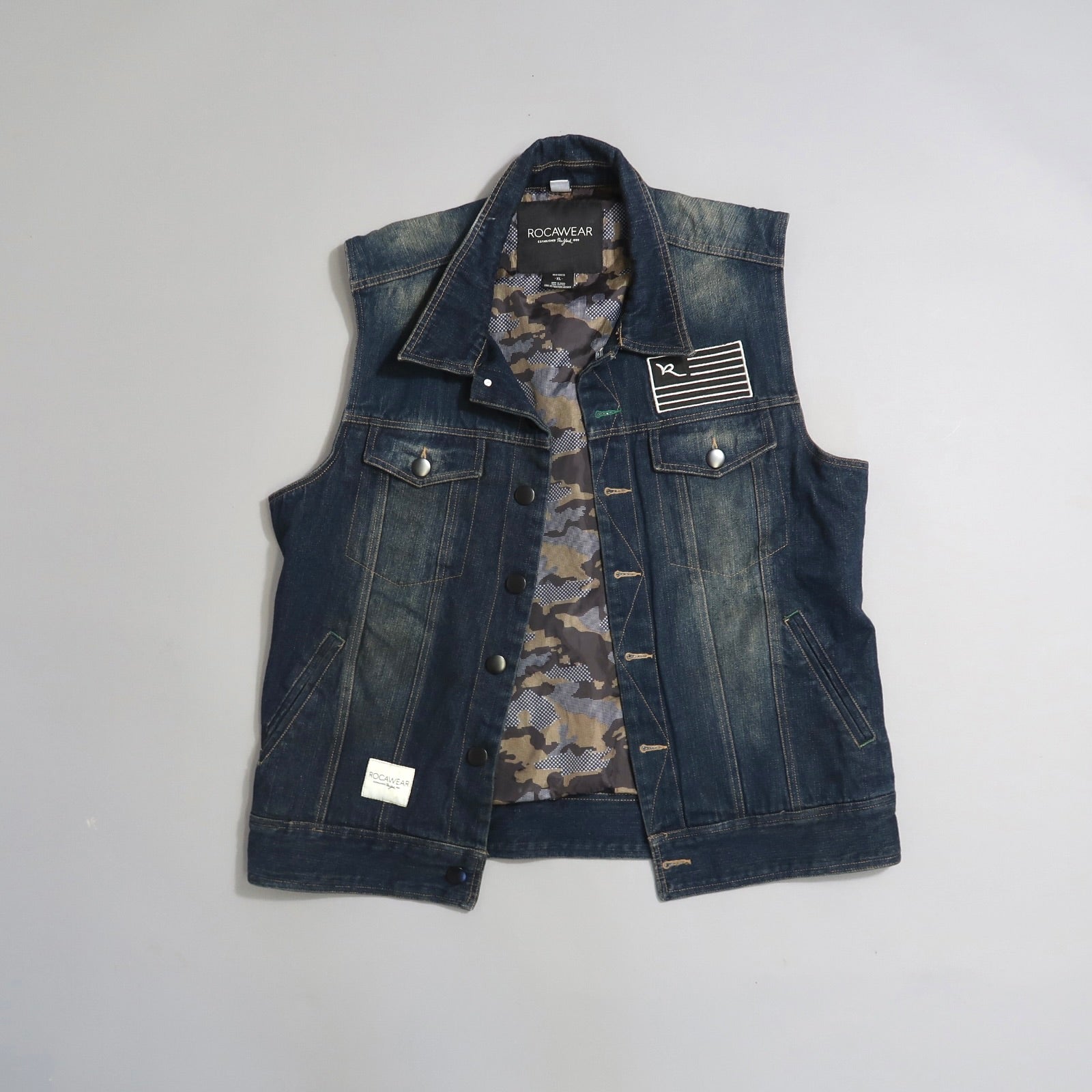 Denim vest with camouflage lining and logo patch on chest.