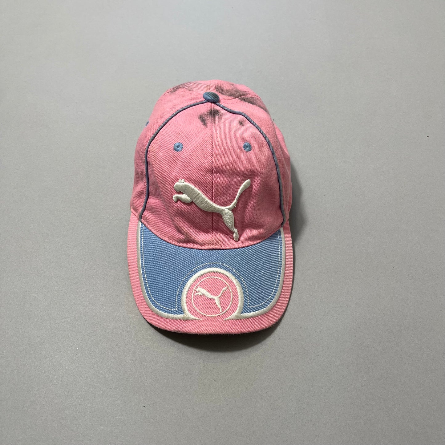 Pink and blue cap with Puma logo on a gray background.